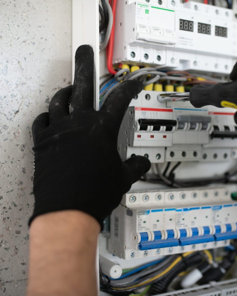A male electrician works in a switchboard.
